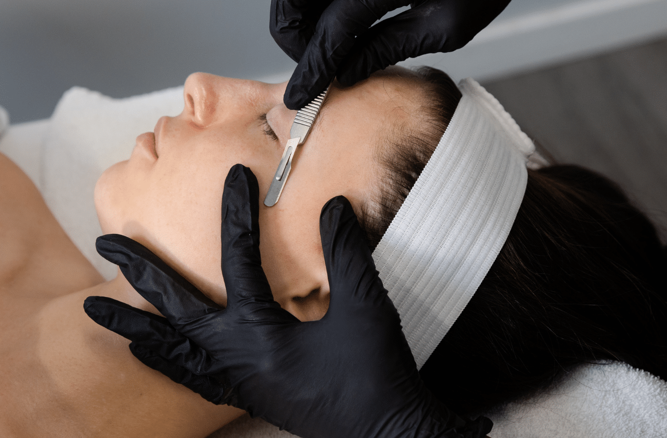 Close-up of a dermaplaning blade gliding across a client's cheek during treatment