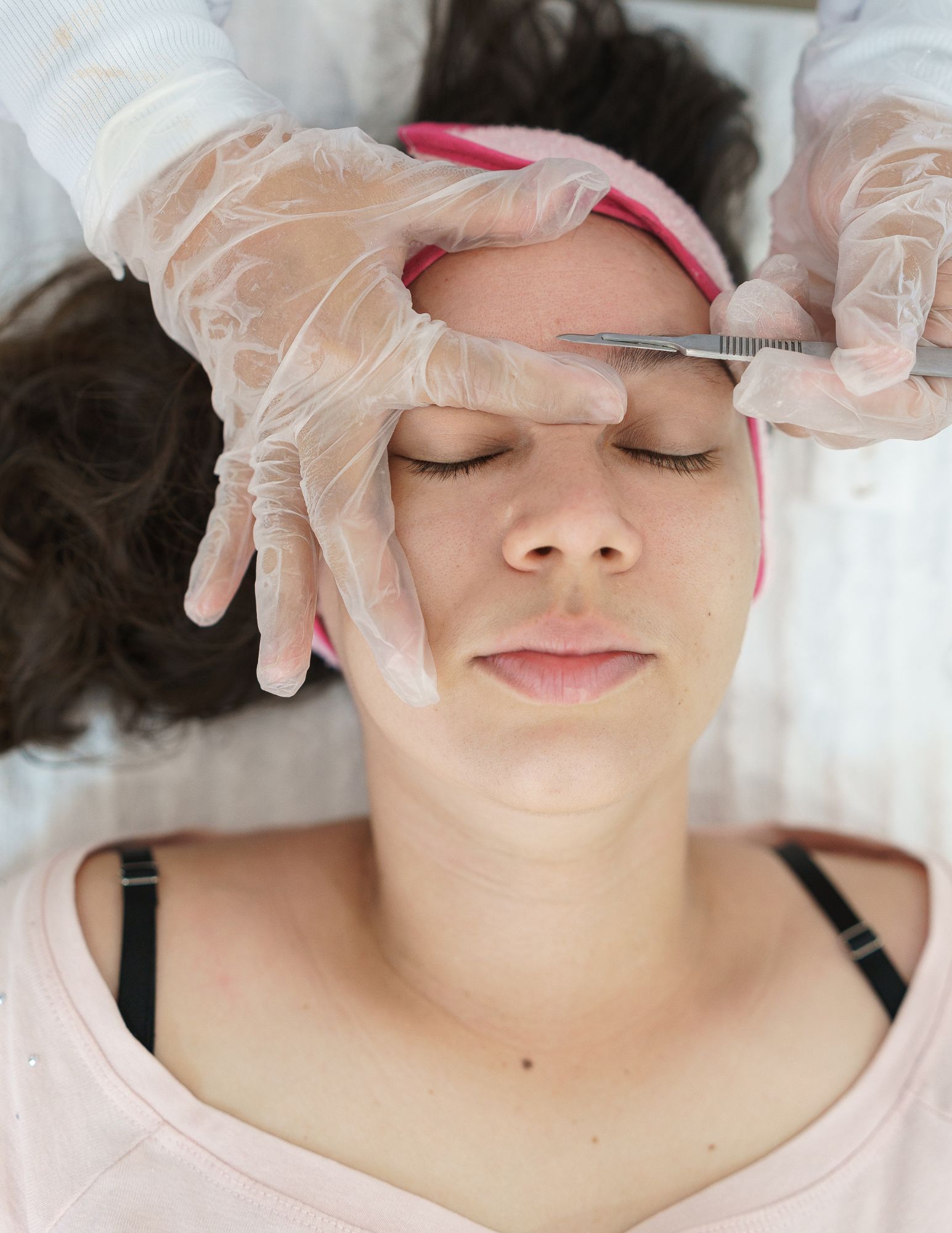 Esthetician performing a dermaplaning treatment on a client's forehead